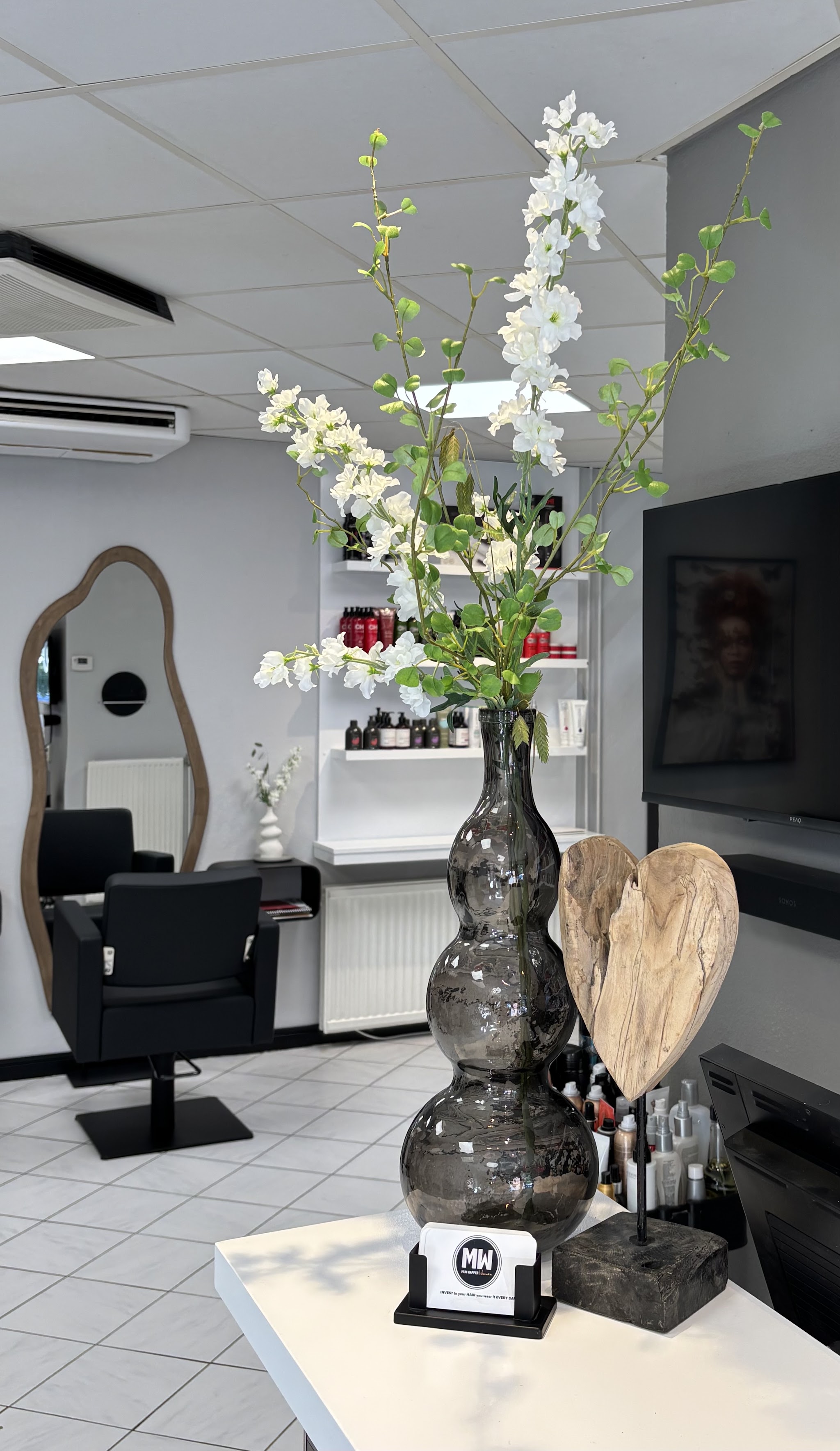 Bloemen en een kappersstoel bij een van de spiegels